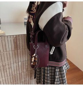 Detail of burgundy woven mini bag with colorful wooden bead tassel and silver hardware