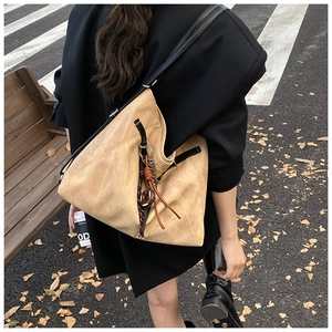 Macro detail of khaki suede tote bag with brown woven leather tassel and wide shoulder strap