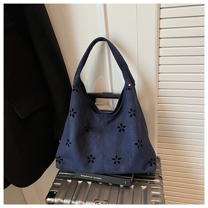 Détail du motif floral découpé au laser sur le sac hobo en daim bleu marine