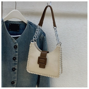 Détail des coutures contrastées et de la bandoulière en chaîne sur sac bandoulière beige