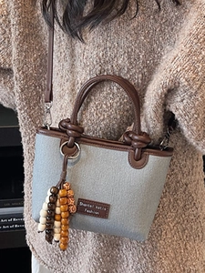 Minimalist canvas bucket bag with brown leather trim and decorative wooden beads