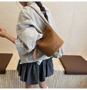 Détail d'un sac seau en daim marron avec un petit porte-monnaie rond amovible