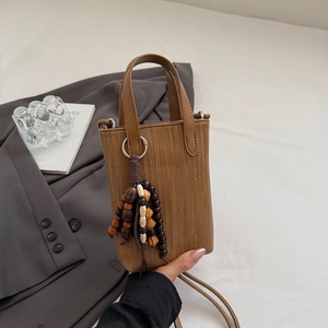 Close-up of brown woven texture mini bag featuring unique wooden bead tassel detail