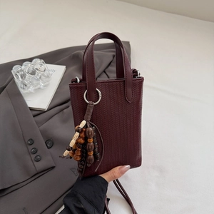 Detail view of burgundy woven texture mini crossbody bag with wooden bead charm