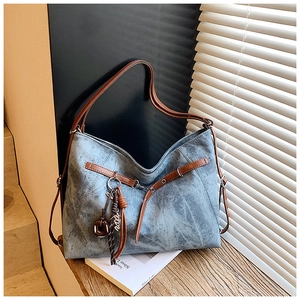Detail of blue washed leather tote bag with brown straps and decorative hanging charms