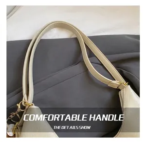 Detail showing the cream faux leather texture and gold hardware rings of the tote bag