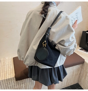 Détail d'un sac seau en daim noir avec anneaux dorés et charm porte-monnaie rond attaché