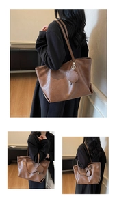 Detail view of large caramel tote bag with double straps and small round coin purse charm