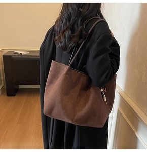 Detailansicht einer braunen Wildleder-Tragetasche mit einem Vintage-Perlenanhänger-Akzent