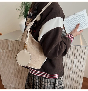 Détail du sac seau en daim beige avec un porte-monnaie rond et une bandoulière nouée
