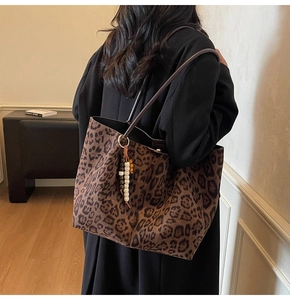 Detail der Vintage-Tasche mit Leopardenmuster und buntem Perlenanhänger am Schultergurt