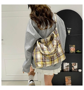 Detail view of the checkered tote bag wide shoulder strap and woven fabric texture