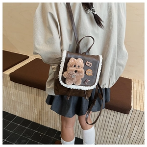 Detail view of small brown vintage leather backpack with plush dog charm and embroidery
