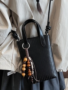 Minimalist black woven mini tote bag with wooden bead charm and long shoulder strap