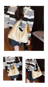 Detail of off-white hobo bag with crescent design and plush bear charm on model
