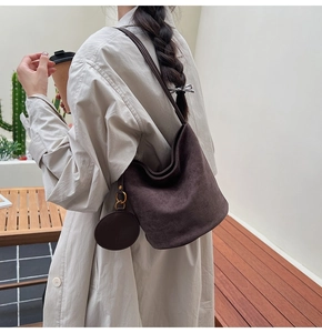 Détail du sac seau en daim marron foncé avec un mini porte-monnaie rond et boucle en métal