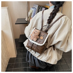 Detail of vintage brown leather backpack with fuzzy faux fur trim and cute bear charm