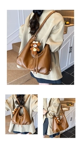 Detail view of large brown retro leather tote bag with fringes and bear pendant