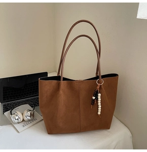 Nahaufnahme der braunen Wildleder-Tote-Bag mit Holzperlen und langen Henkeln am Tisch