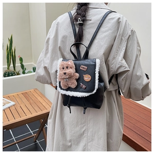 Detail of cute black leather backpack with fuzzy white trim and plush bear charm