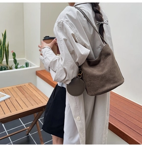 Détail du sac seau en daim marron avec petite pochette ronde assortie porté à l'épaule