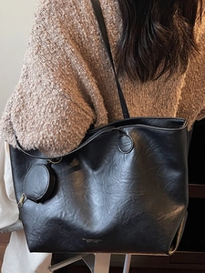 Large black faux leather tote bag with small coin purse shown on a model's shoulder