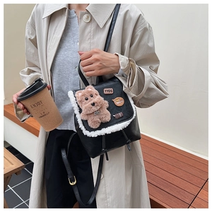 Detail of a black mini backpack with white fleece trim and a cute plush puppy charm