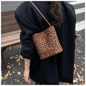 Close-up of leopard print bucket bag with faux fur texture and brown slim shoulder strap
