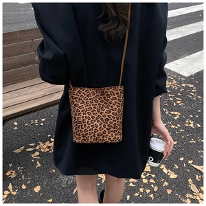 Mini leopard print bucket bag with brown strap shown in a street style casual setting