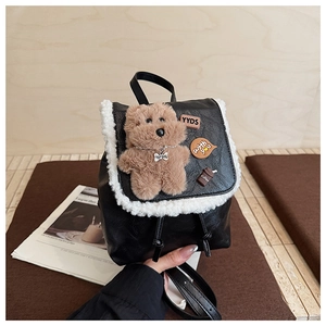 Detail of black leather mini backpack with plush teddy bear and stylish patches