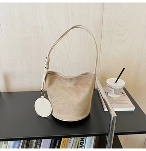 Détail d'un sac seau en daim beige avec garniture en cuir et porte-monnaie rond