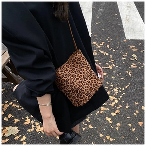 Outdoor shot showing a mini leopard print bucket bag with brown strap on autumn street