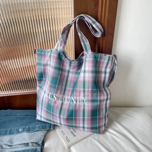 Macro shot of plaid canvas tote with YES HONEY embroidery and checkered fabric detail