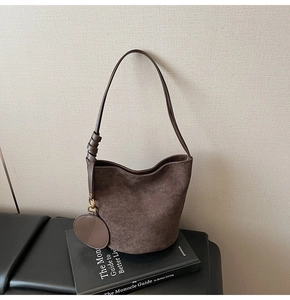 Détail de la texture d'un sac seau en daim marron avec petit porte-monnaie sur un livre