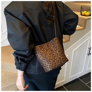 Close-up of leopard print bucket bag with slim shoulder strap worn on person
