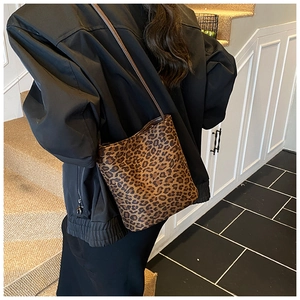 Fashionable leopard print bucket bag with slim shoulder strap shown on a model