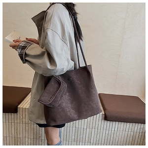 Dettaglio della borsa tote in pelle PU marrone scuro con logo metallico e mini pochette coordinata