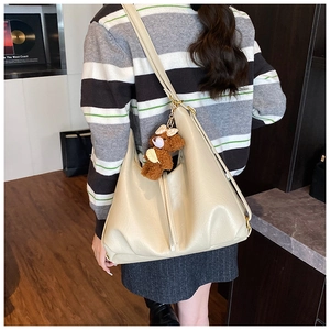 Detailed close-up of cream tote bag with pebble leather texture and brown bear pendant