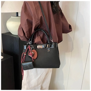 Detail of black fabric handbag with silver metal twist lock and unique charms hanging on handle
