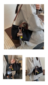Détail du sac seau en toile noire avec poignées en cuir marron et pendentif smiley joyeux
