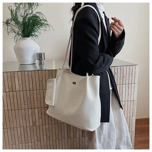 Vista laterale della borsa tote in pelle bianca con ciondolo quadrato e logo sul modello