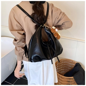 Detail view of large black soft PU leather tote bag worn by a model with a bear charm