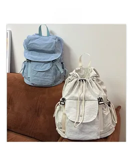 Detail view of nylon travel backpacks in blue and beige with drawstring and buckle closure
