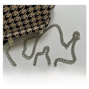 Close-up of houndstooth woven handbag featuring a premium silver metal chain strap