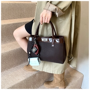 Detail of dark brown handbag with silver twist lock and unique miniature book charms