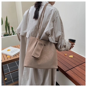 Dettaglio della borsa a secchiello beige minimalista con astuccio coordinato
