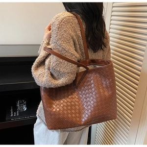 Detailed close-up of brown woven PU leather tote bag with elegant handle detail