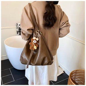 Detail view of large brown vintage tote bag with plush bear charm on back of a model
