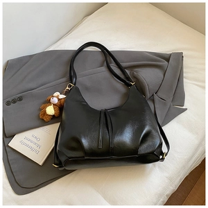 Detail of black faux leather tote bag with a cute brown plush bear charm accessory