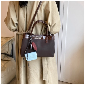 Detailed close-up of a two-tone PU leather handbag with metal twist lock and decorative charms